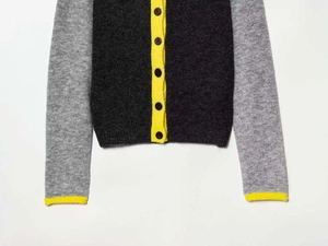 Detailed macro view of gray knit cardigan featuring yellow trim and dark round buttons