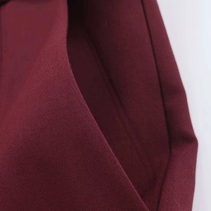 Detailed close-up of side pockets on burgundy tailored trousers with fine stitching