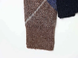 Detail of ribbed cuffs and fuzzy argyle knit texture in navy and brown colors