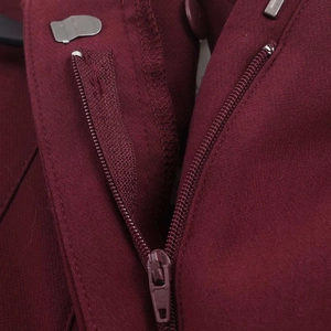 Detail view of the metal hook closure and matching zipper on burgundy tailored trousers
