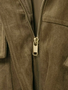 Gros plan d'une veste en daim vert olive avec fermeture éclair et coutures soignées