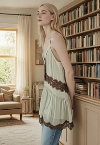 Detail of light green camisole top with dark brown lace trim and tiered hem design