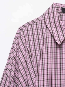 Detailed macro view of the classic notched collar and pink plaid texture on the shirt