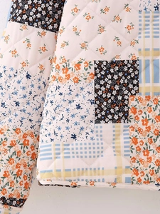 Detailed view of quilted cotton jacket with patchwork floral patterns and diamond stitching