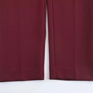 Detail view of burgundy trousers leg hem showing smooth fabric and neat stitching