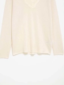 Détail de l'élégant col en V en dentelle sur ce pull en maille minimaliste de couleur crème
