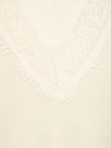 Gros plan du col en V avec bordure en dentelle délicate sur ce pull en maille ivoire