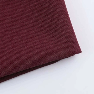 Detail shot of the deep burgundy woven fabric texture on professional slim fit suit pants