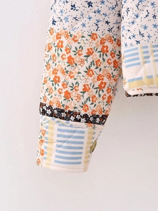 Detail of quilted jacket cuff featuring floral patchwork patterns and a single button