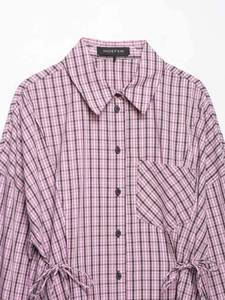 Detail of pink plaid shirt featuring adjustable side drawstrings and black button front
