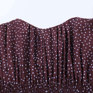 Detalle del escote de blusa marrón con lunares azules y delicados pliegues elásticos