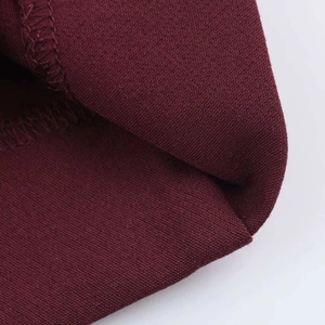 Detailed macro view of burgundy knit fabric with clean stitched rolled hem finish