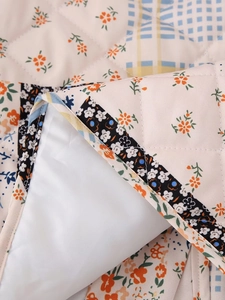 Detailed macro view of diamond quilted cotton fabric with vintage floral and plaid patterns