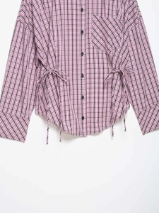 Close-up of pink and brown plaid shirt featuring side drawstring and buttoned chest pocket