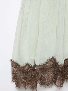Macro detail of mint green pleated fabric with contrast dark brown eyelash lace trim
