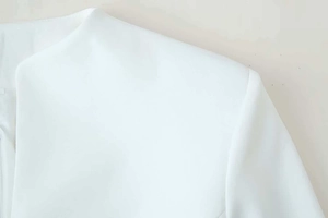Detail of white tailored bodice with textured fabric and precise shoulder stitching