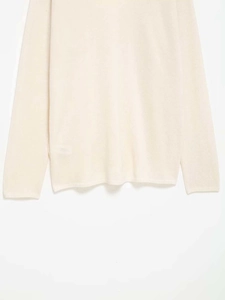 Gros plan sur l'ourlet en dentelle et la maille de ce pull crème à manches longues