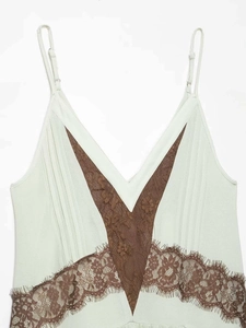 Close-up of mint green pleated dress with V-neckline and brown floral lace trim