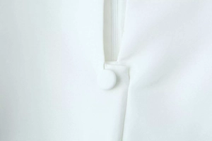 Close-up of fabric-covered button and seamless invisible zipper on white dress waist