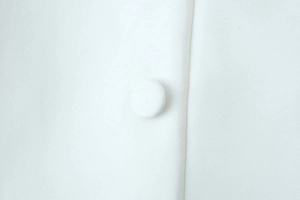Detailed macro view of white dress fabric with textured weave and fabric-covered button