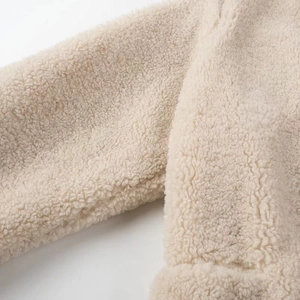 Close-up of beige plush sherpa fleece fabric showing thick and soft curly texture