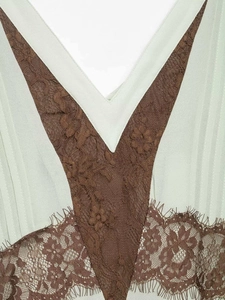 Close-up of V-neckline with delicate eyelash lace trim and green pleated fabric detail