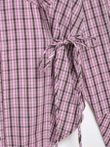 Detail of pink and brown plaid shirt featuring side drawstring and fabric texture