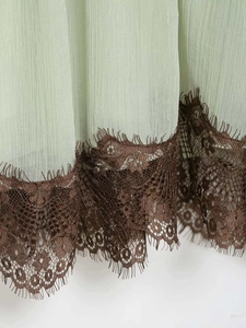 Detail of light green pleated chiffon hem with dark brown eyelash lace trim