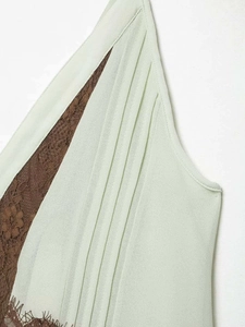 Detail of light green chiffon dress with brown floral lace insert and pleats