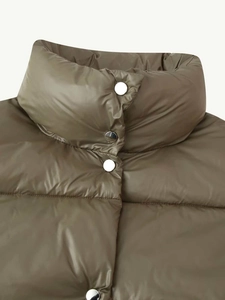 Detail of olive green puffer jacket featuring high collar and silver snap buttons