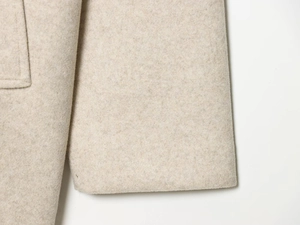 Gros plan sur le manteau en laine beige montrant les coutures et la texture du tissu