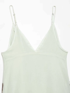 Detailed close-up of adjustable metal buckle on thin shoulder strap of light green dress