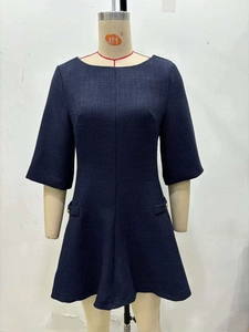 Detail of navy tweed dress showing textured fabric and flap pockets with gold buttons