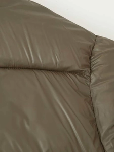 Detailed close-up of dark olive green puffer jacket with quilted high-shine fabric