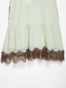 Detailed close-up of mint green fabric with vintage dark brown eyelash lace trim