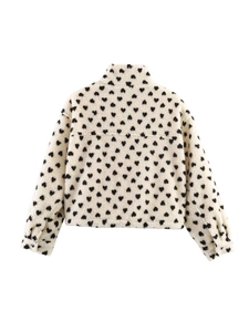 Détail du tissu polaire beige avec motifs de cœurs noirs sur la veste chic