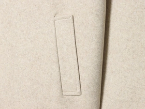 Vue macro détaillée de la texture en laine et de la poche cousue sur le manteau blanc cassé