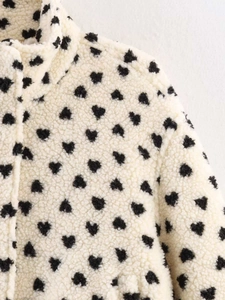Détail d'une veste en polaire crème avec motifs cœurs noirs et col montant ajusté