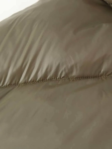 Close-up of olive green quilted puffer jacket fabric showing smooth synthetic texture