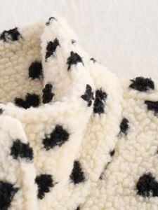 Gros plan détaillé du tissu sherpa beige doux orné de motifs à pois noirs élégants