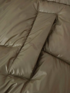 Detail of olive green winter puffer jacket featuring horizontal quilting and fine stitching