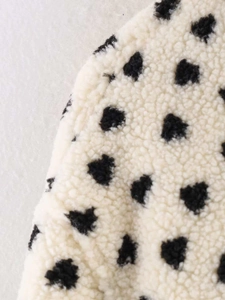 Gros plan détaillé sur la texture polaire sherpa blanc cassé à pois noirs