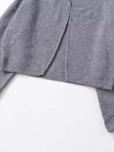 Detaillierte Makroansicht der grauen Strickjacke, Stoffstruktur und Saumverarbeitung