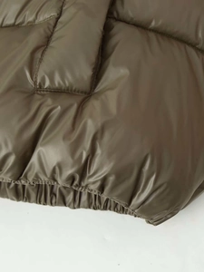 Detail of olive green puffer jacket showing quilted texture and premium matte fabric finish
