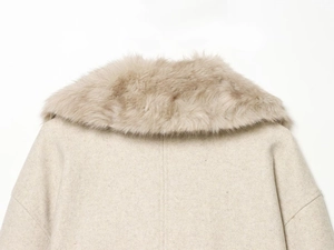 Détail d'un manteau en laine beige avec col en fausse fourrure et épaules tombantes