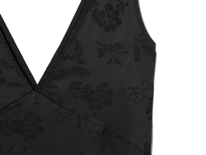 Macro detail of black jacquard fabric with rose floral pattern on a V-neck dress