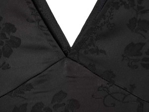 Detailed close-up of black jacquard fabric with elegant floral pattern on a deep V-neck dress