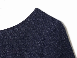 Close-up detail of dark blue tweed dress showing textured weave and neckline craftsmanship