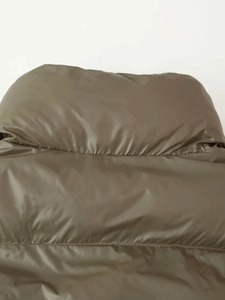 Close-up of olive green quilted puffer jacket featuring high collar and glossy fabric texture