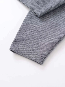 Detailaufnahme der gerippten Strickstruktur und Bündchen an einem hellgrauen Cardigan